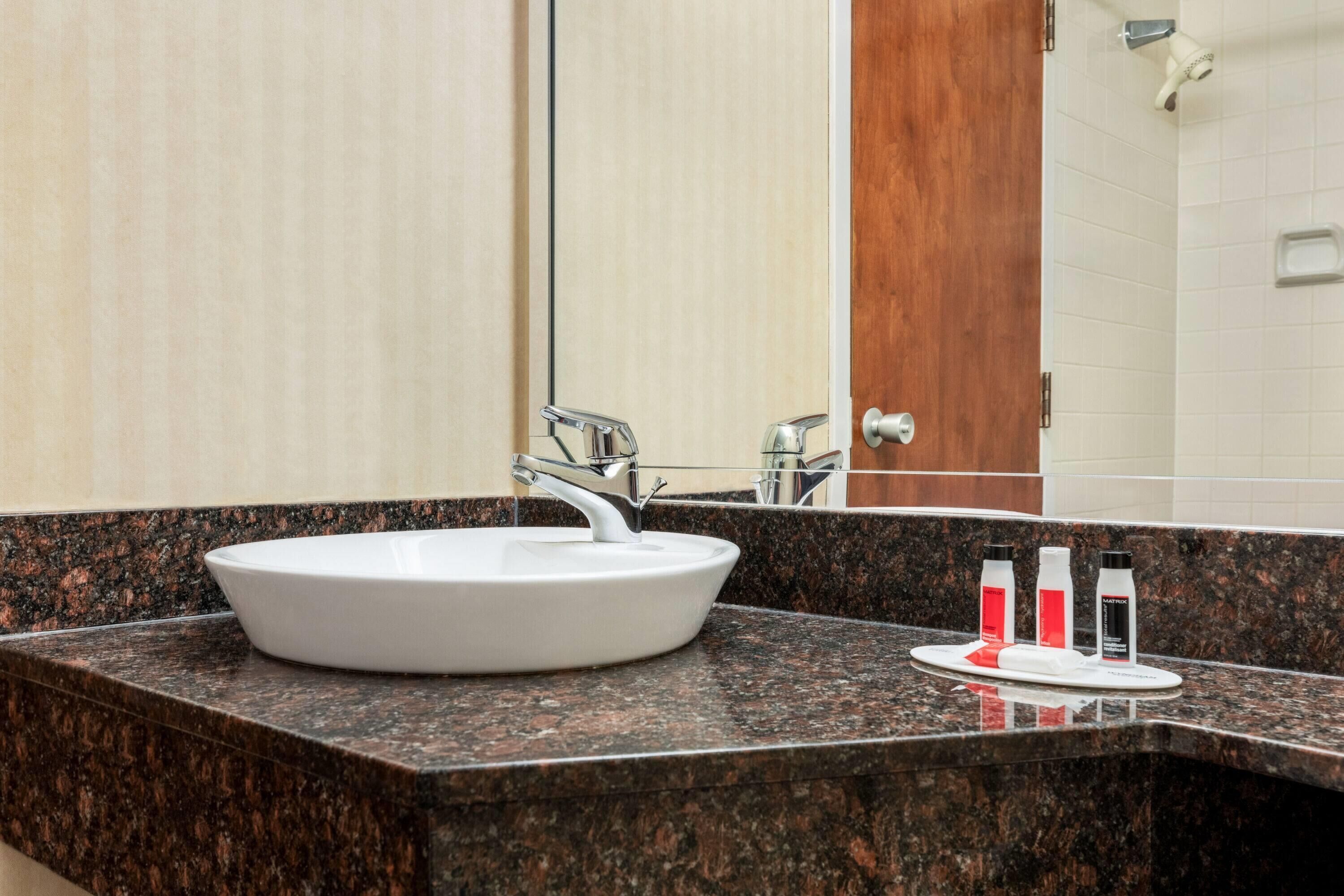 Une salle de bain avec un lavabo blanc, un miroir et une porte en bois.