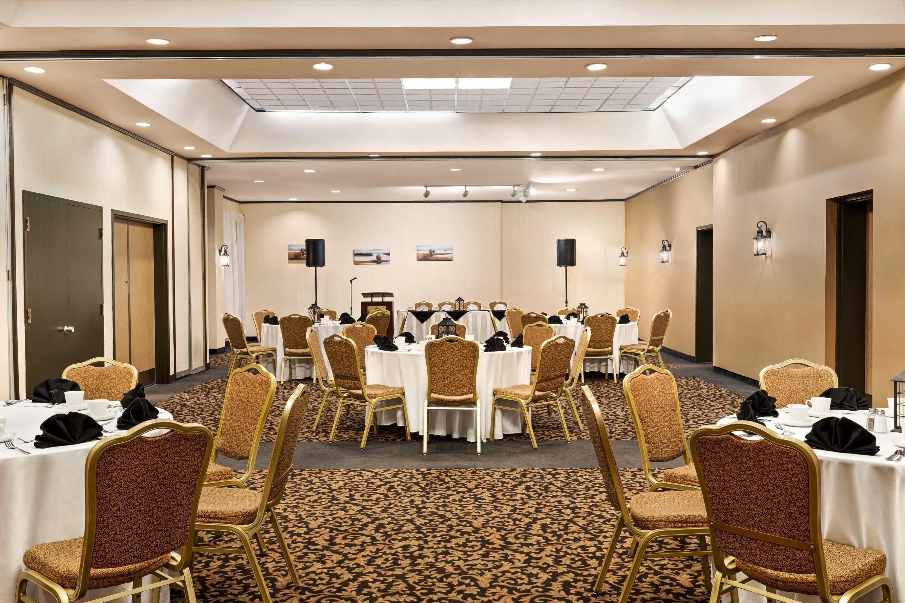 A conference room with round tables, chairs, and a carpeted floor.