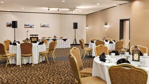 A conference room with round tables, gold chairs, white tablecloths, and a carpeted floor. - Ramada by Wyndham Fredericton (Fredericton)