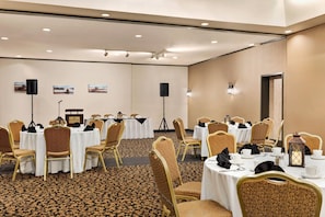 A conference room with round tables, gold chairs, white tablecloths, and a carpeted floor. - Ramada by Wyndham Fredericton (Fredericton)