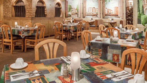 A restaurant interior with wooden walls, stone accents, and tables set with tableware. - Ramada by Wyndham Fredericton (Fredericton)