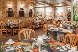 Interior de restaurante con paredes de madera, detalles de piedra y mesas dispuestas con vajilla.