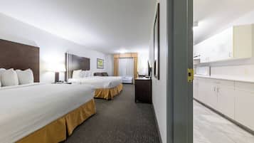 Une chambre d’hôtel avec deux lits, un bureau et une kitchenette.