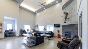 Un vestíbulo amplio con un diseño moderno, que cuenta con una zona de estar con sofás y sillones, una mesa de centro, una chimenea y un televisor montado.