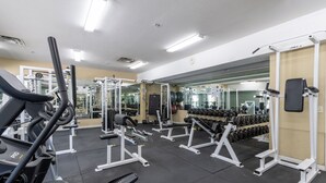 Un gimnasio con cintas de correr, máquinas de pesas y pesas sueltas.