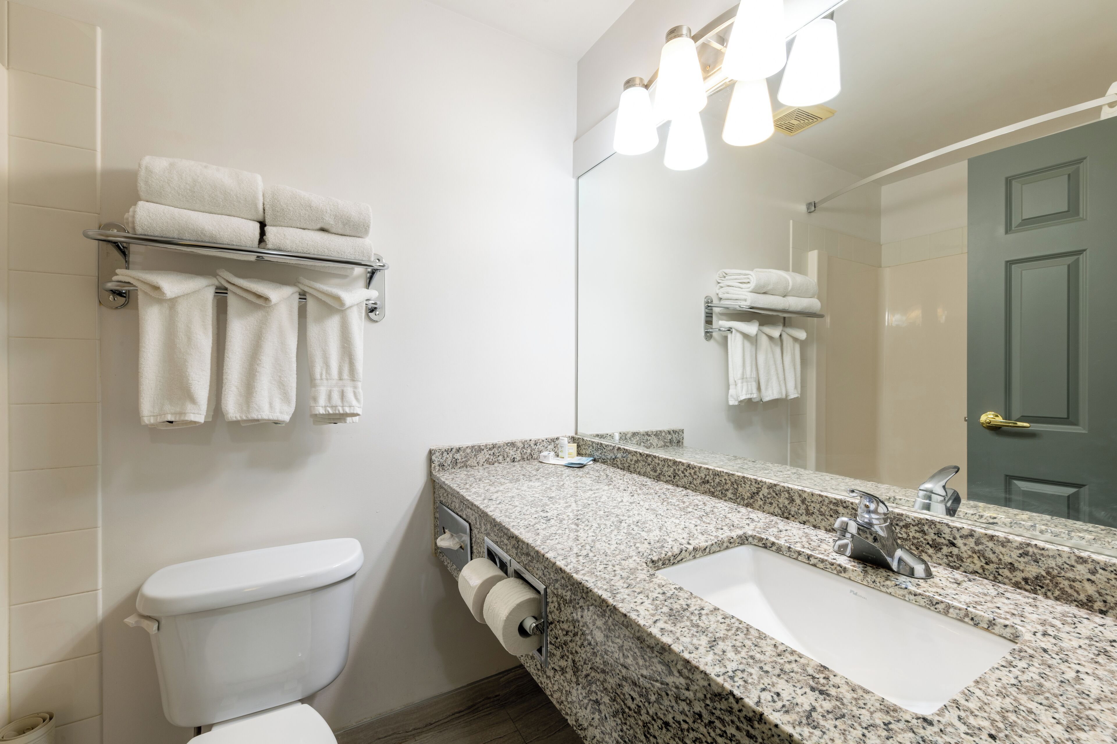 Un baño con inodoro, lavamanos y toallero.