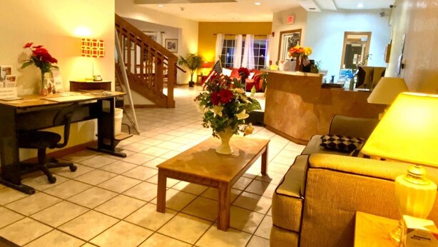 A hotel lobby with a reception desk, a staircase, a sofa, and a coffee table.