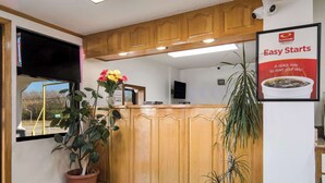 A reception area with wooden cabinets, a flat-screen TV, potted plants, and a poster advertising 'Easy Starts'. - Econo Lodge Calhoun North Damascus (Calhoun)