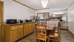 A kitchen with wooden cabinets, a dining table, and chairs. There is a microwave, coffee maker, and other appliances on the counter. - Econo Lodge Calhoun North Damascus (Calhoun)