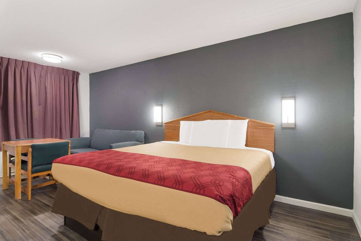 Una habitación de hotel con una cama, un escritorio, una silla y una ventana.