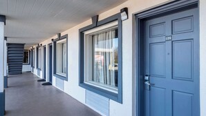 A corridor with a series of doors, each with a window and a doorbell. - Econo Lodge Calhoun North Damascus (Calhoun)