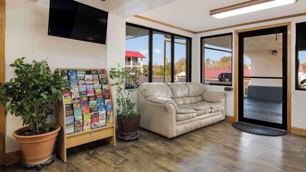 A lobby with a beige sofa, a bookshelf, and a large window offering a view of the outside. - Econo Lodge Calhoun North Damascus (Calhoun)