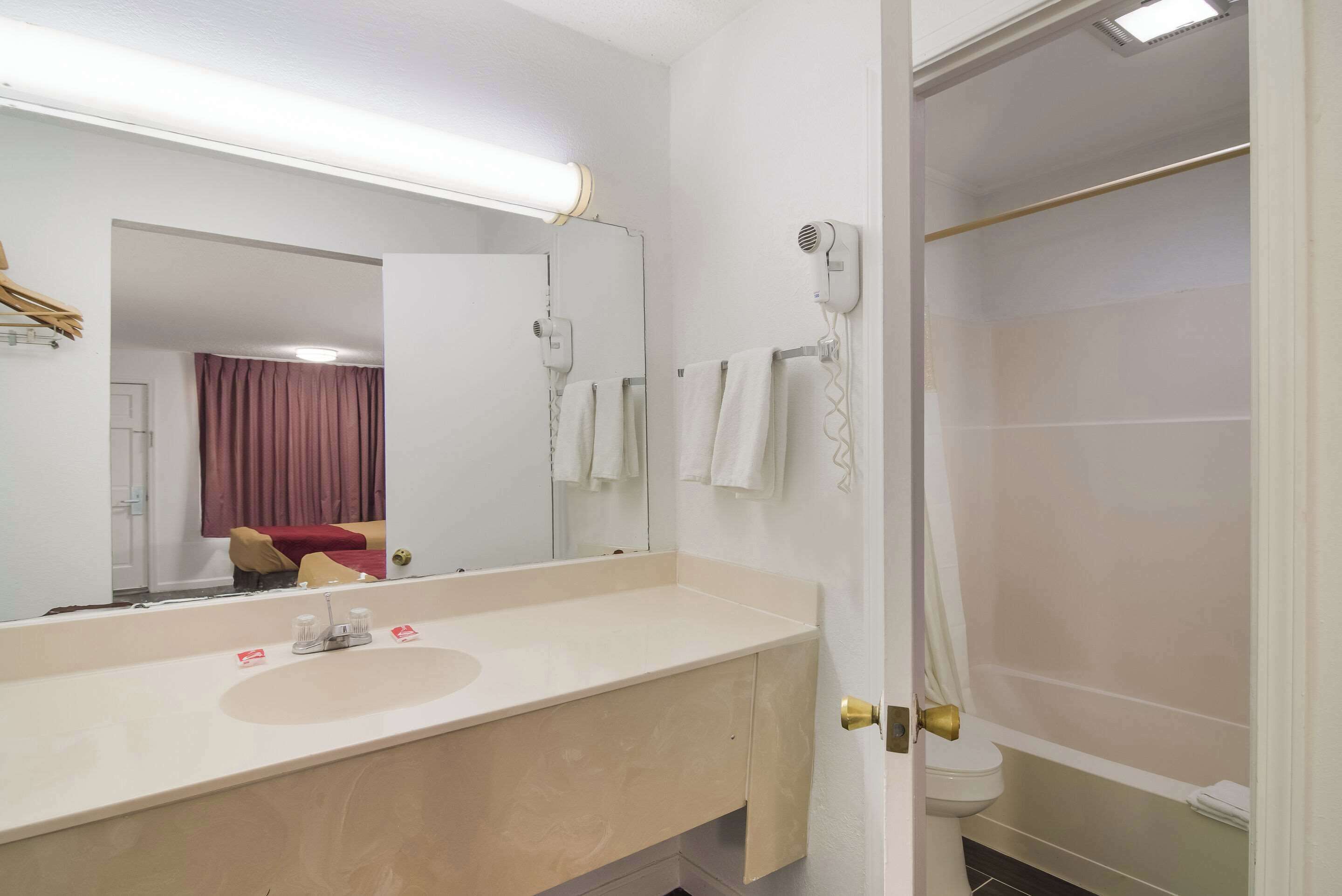 A bathroom with a sink, mirror, towel rack, and a shower area.