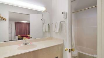 A bathroom with a sink, mirror, towel rack, and a shower area.