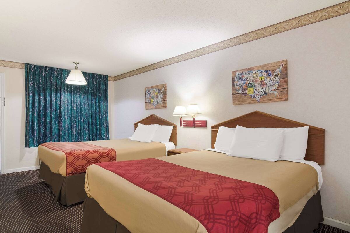 Habitación de hotel con dos camas, una ventana con cortinas, un mapa en la pared y una lámpara en la mesita de noche.