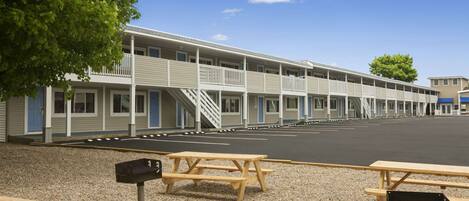 Un motel con varias habitaciones, estacionamiento y mesas de picnic.