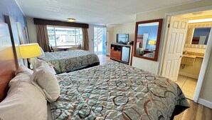 A hotel room with two beds, a desk with a television, a mirror, and a bathroom visible through an open door. - Days Inn by Wyndham West Yarmouth/Hyannis Cape Cod Area (West Yarmouth)