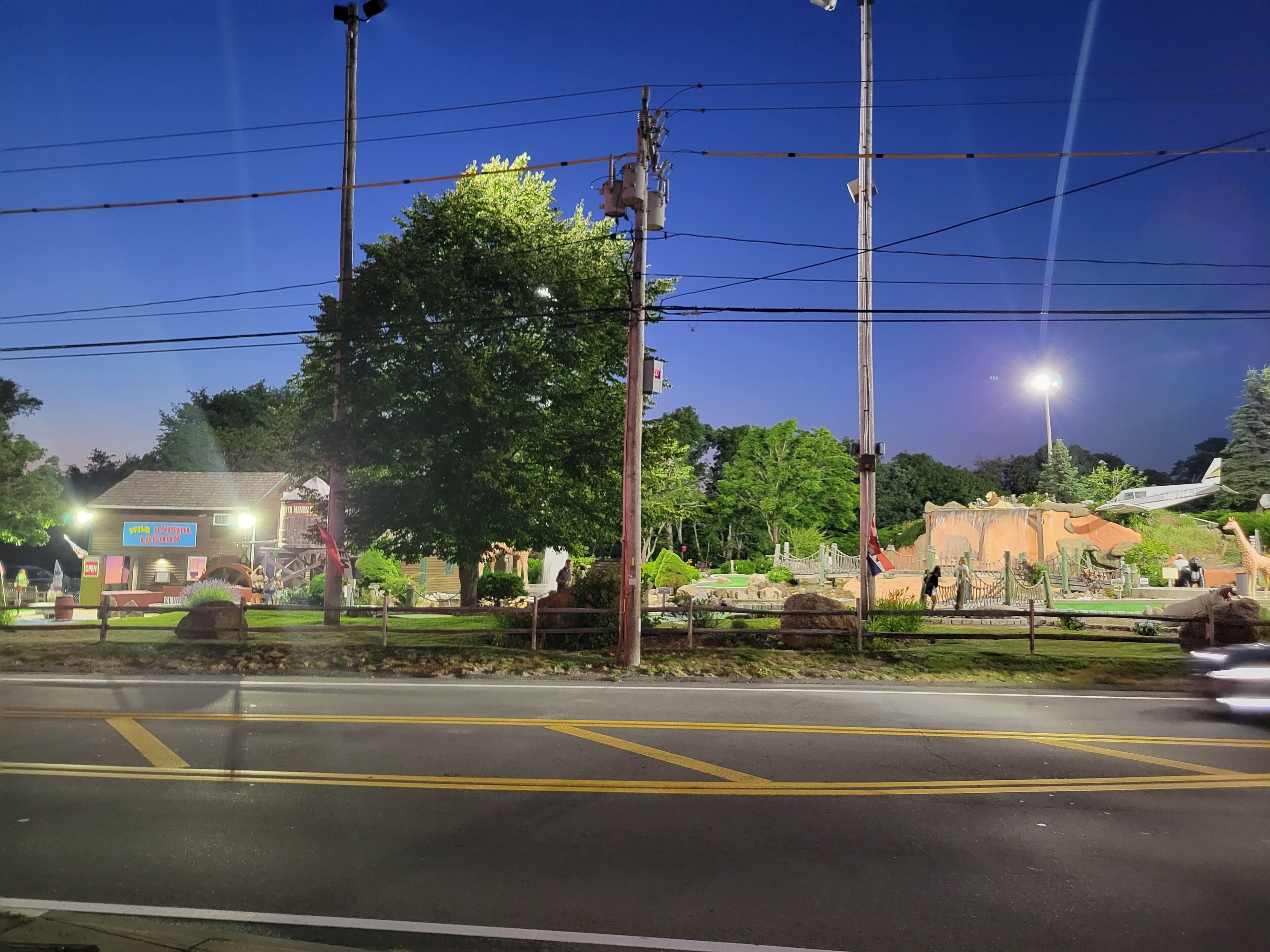 A street view at night with a road marked with yellow lines, streetlights, and a building with a sign that reads "INFORMAL VAGABOND".