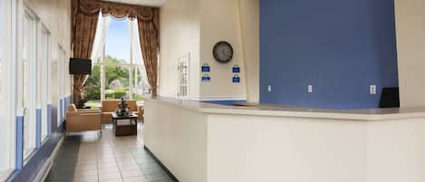 A reception area with a reception desk, a clock, and a window with curtains.