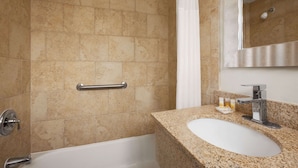 A bathroom with beige tiles, a white sink, and a mirror. - Days Inn by Wyndham West Yarmouth/Hyannis Cape Cod Area (West Yarmouth)