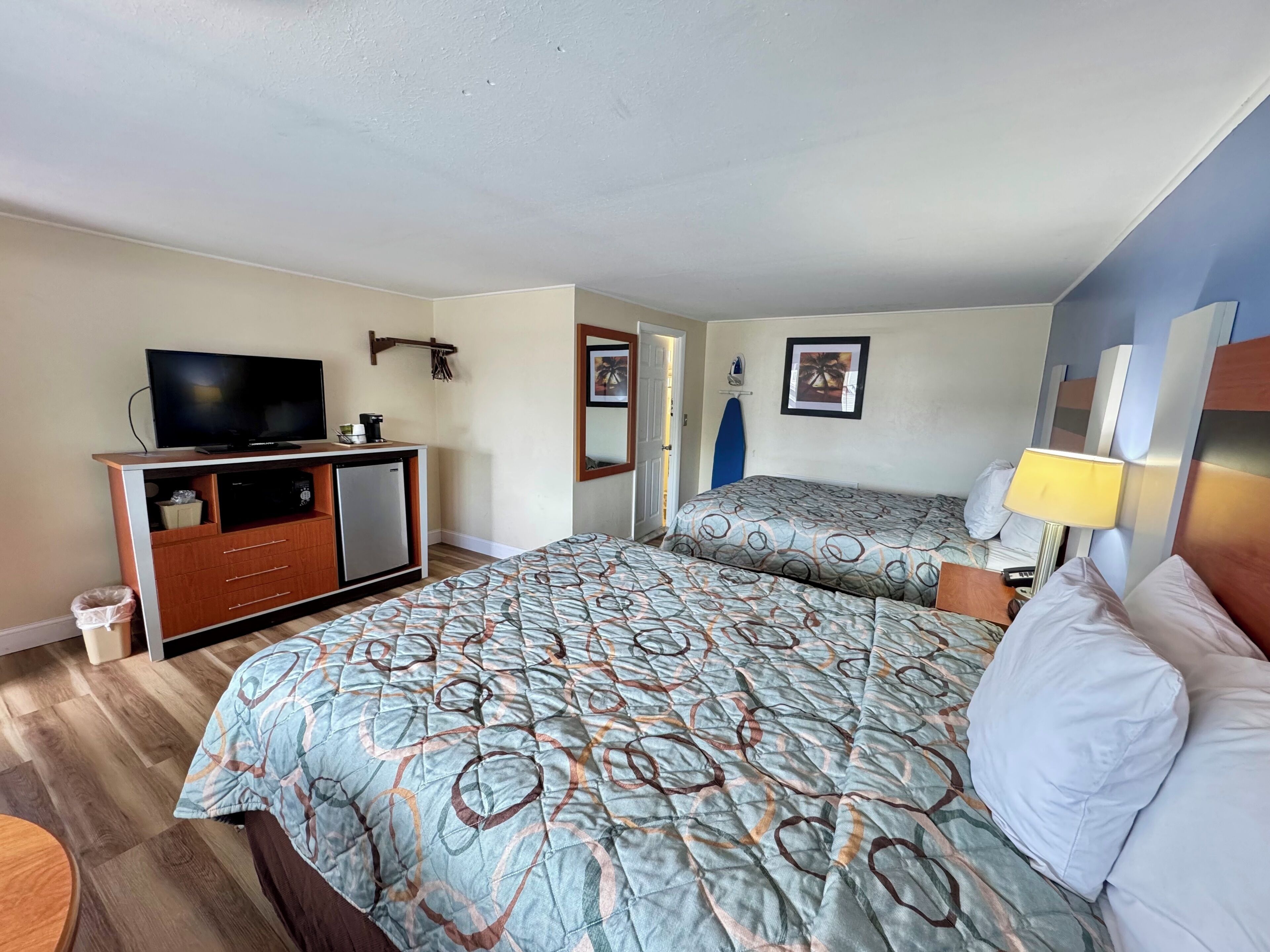 Habitación de hotel con cama, televisión, escritorio y una pequeña cocina.