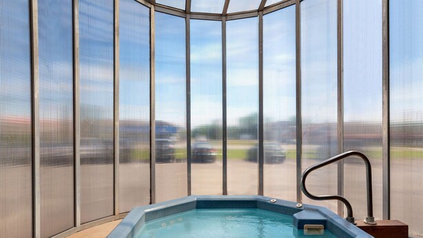A hot tub in a room with large windows and a view of a parking lot. - Days Inn by Wyndham Fredericton (Fredericton)