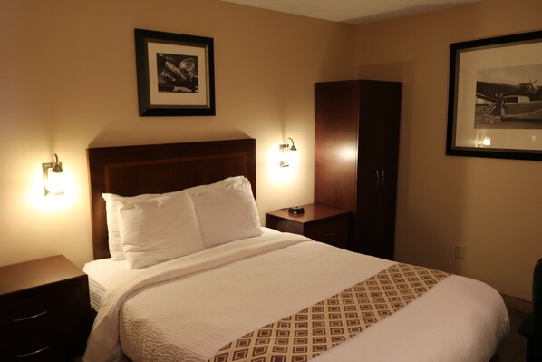 A hotel room with a neatly made bed, two bedside tables, a wardrobe, and two wall-mounted lamps.
