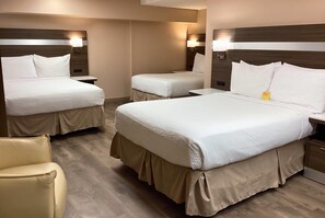 Ein Hotelzimmer mit zwei Betten, einem Sessel und Nachttischen mit Lampen.