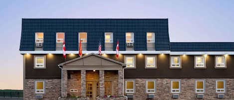 A hotel with a stone facade, multiple windows, and flags.