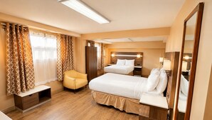 A hotel room with a bed, bedside tables, a chair, a wardrobe, and a mirror. - Days Inn by Wyndham Fredericton (Fredericton)
