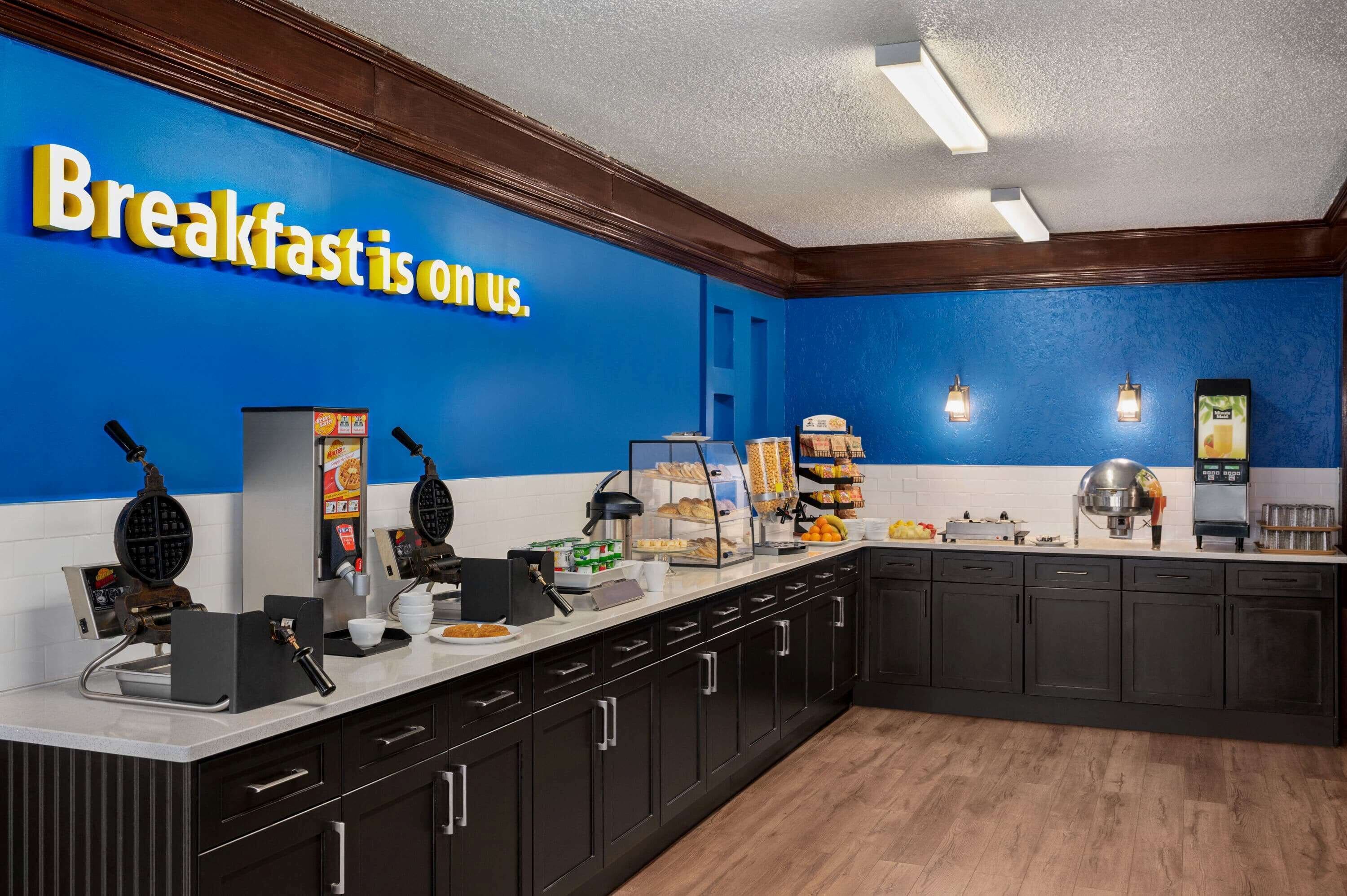 A breakfast station with waffle makers, a coffee machine, and a variety of food items on display.