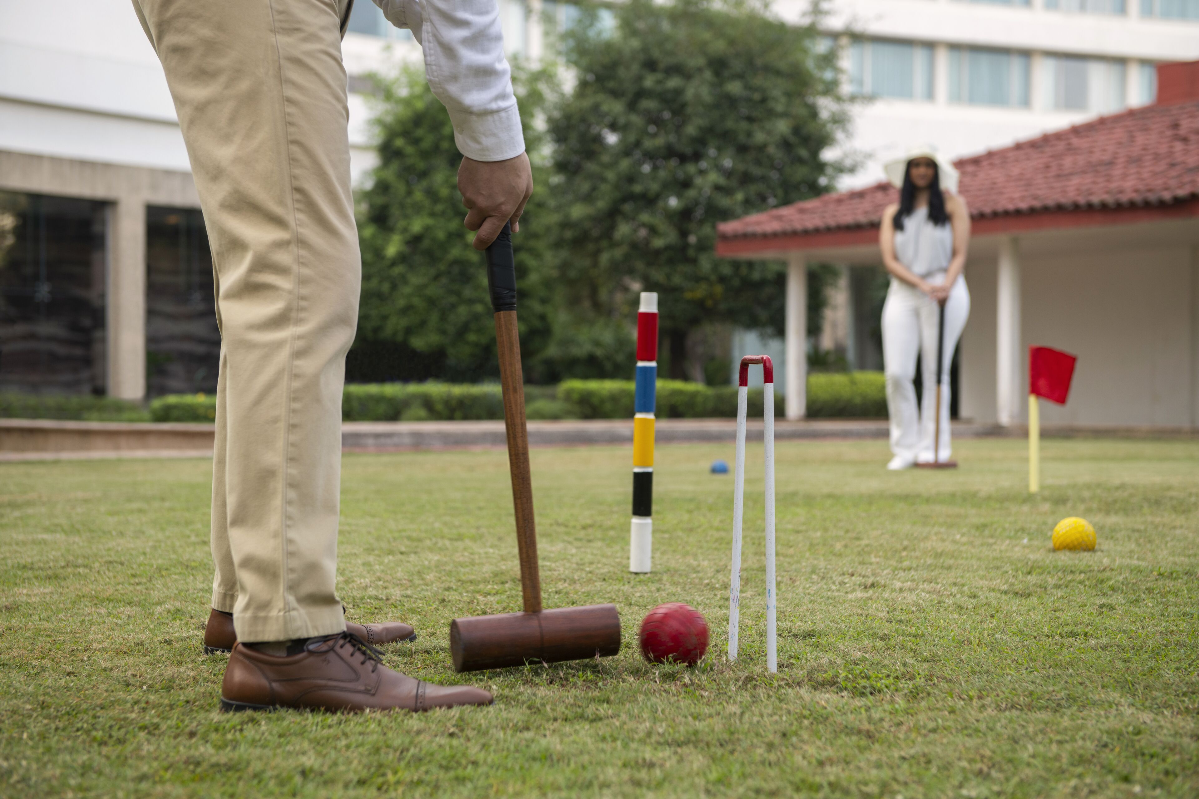 A croquet game in progress with a player in the foreground and another in the background.