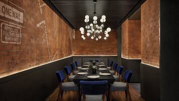 A conference room with a brick wall, a chandelier, and a long table with chairs.