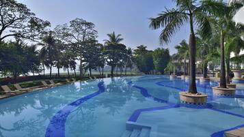 Relax by the serene pool surrounded by lush greenery and lounge chairs.
