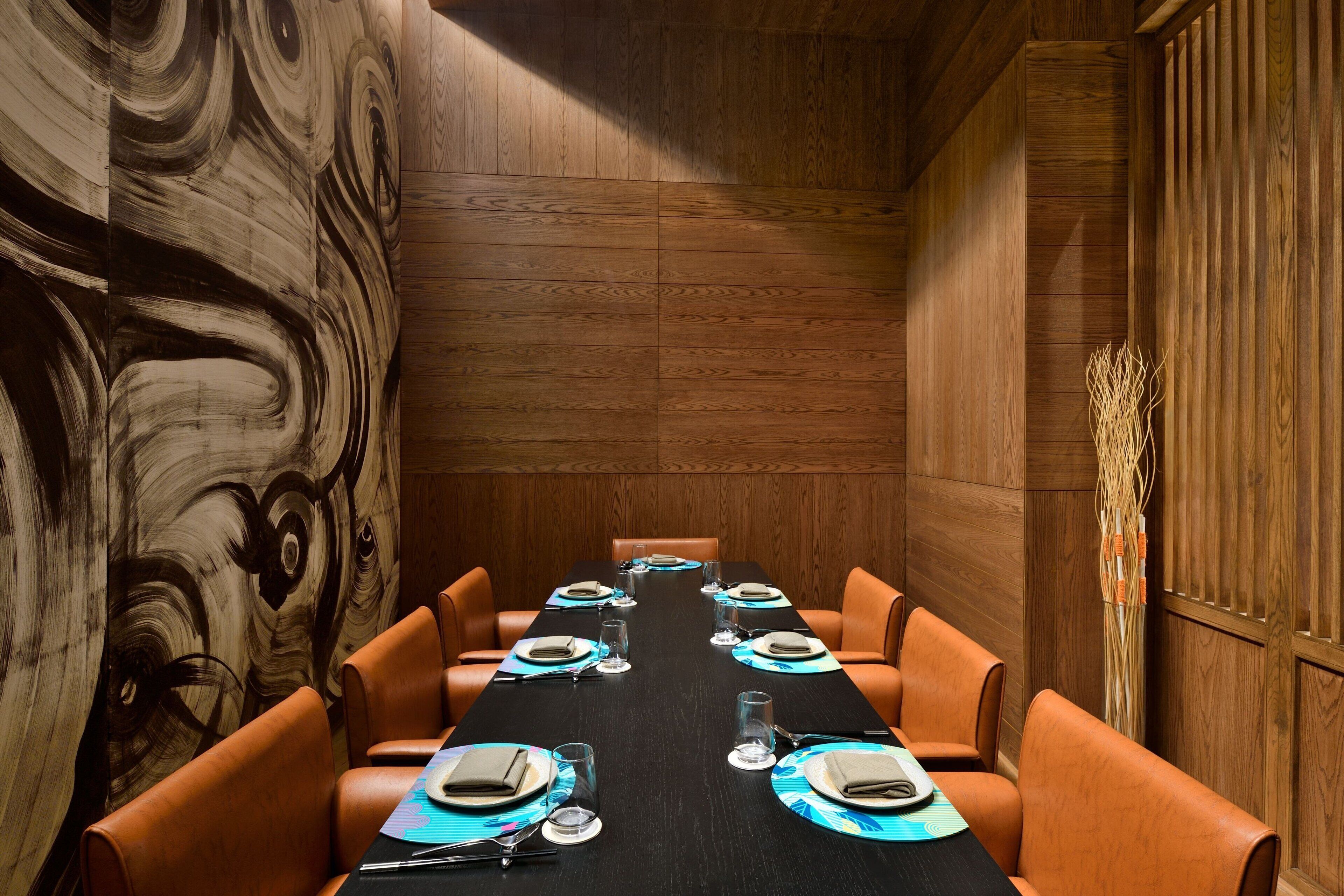 A conference room with a long table set for eight, surrounded by leather chairs.