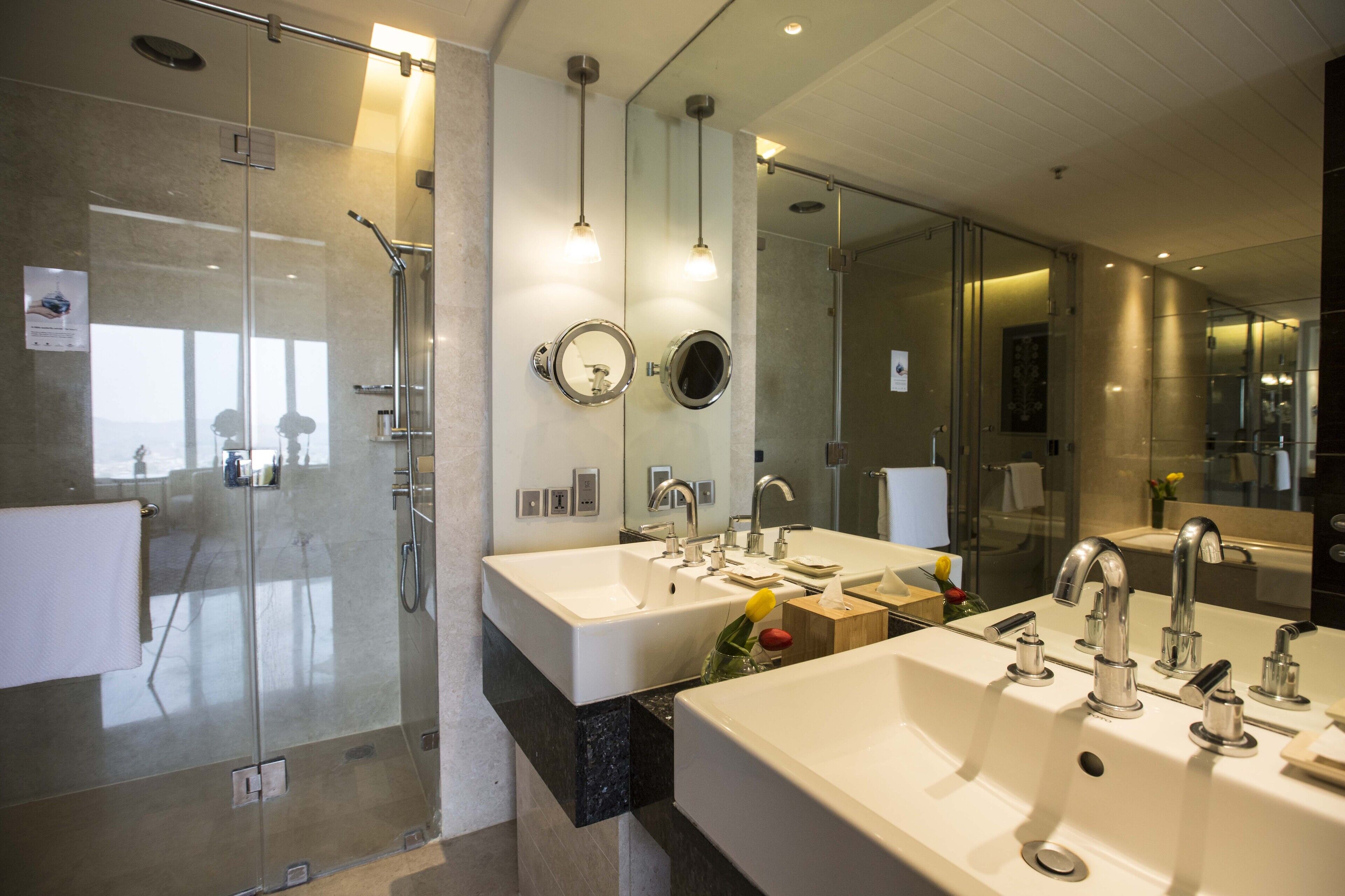 Un baño moderno con dos lavamanos, una cabina de ducha de vidrio y espejos.