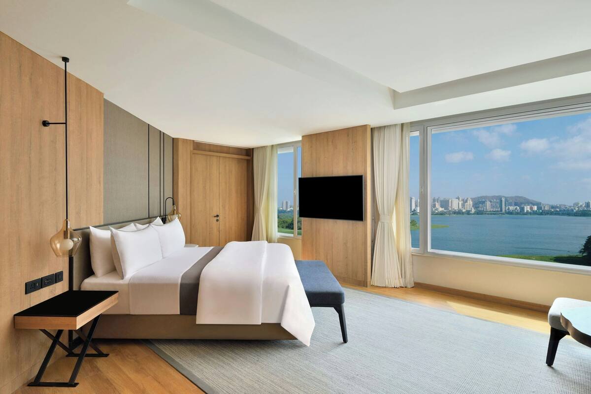 A modern hotel room with a large bed, a desk, and a TV.