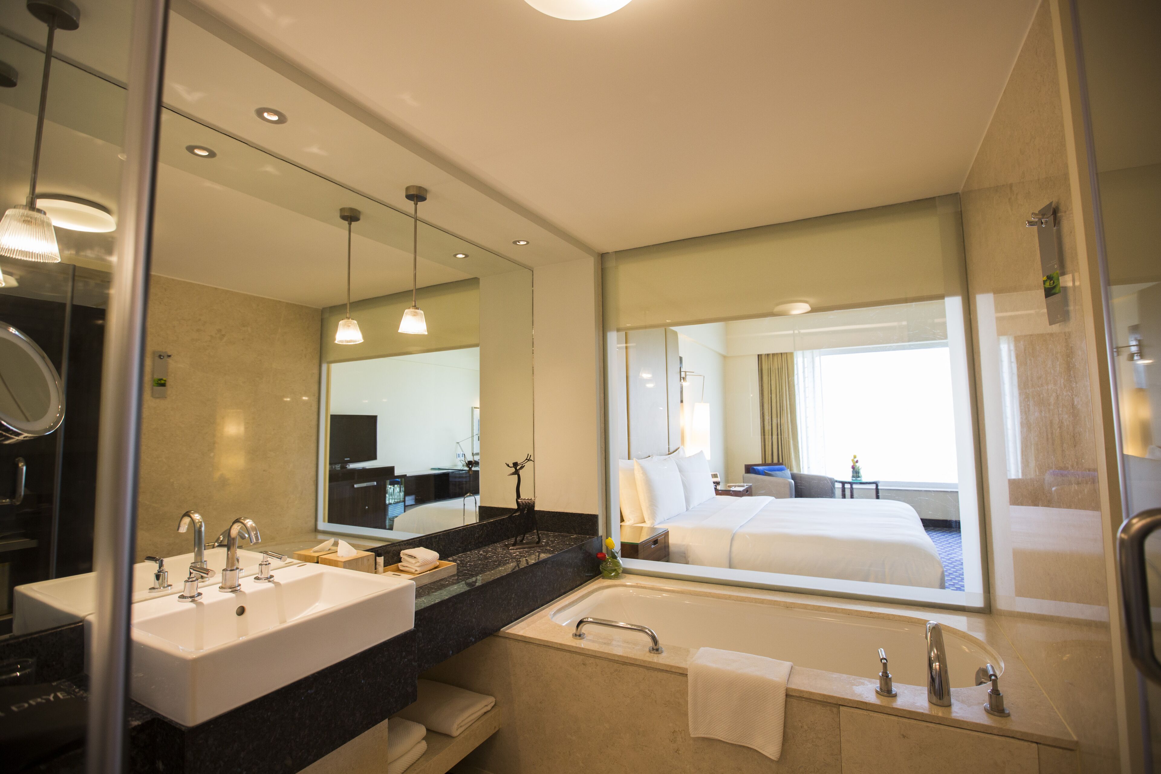 A modern hotel bathroom with dual sinks, a large mirror, and a bathtub.