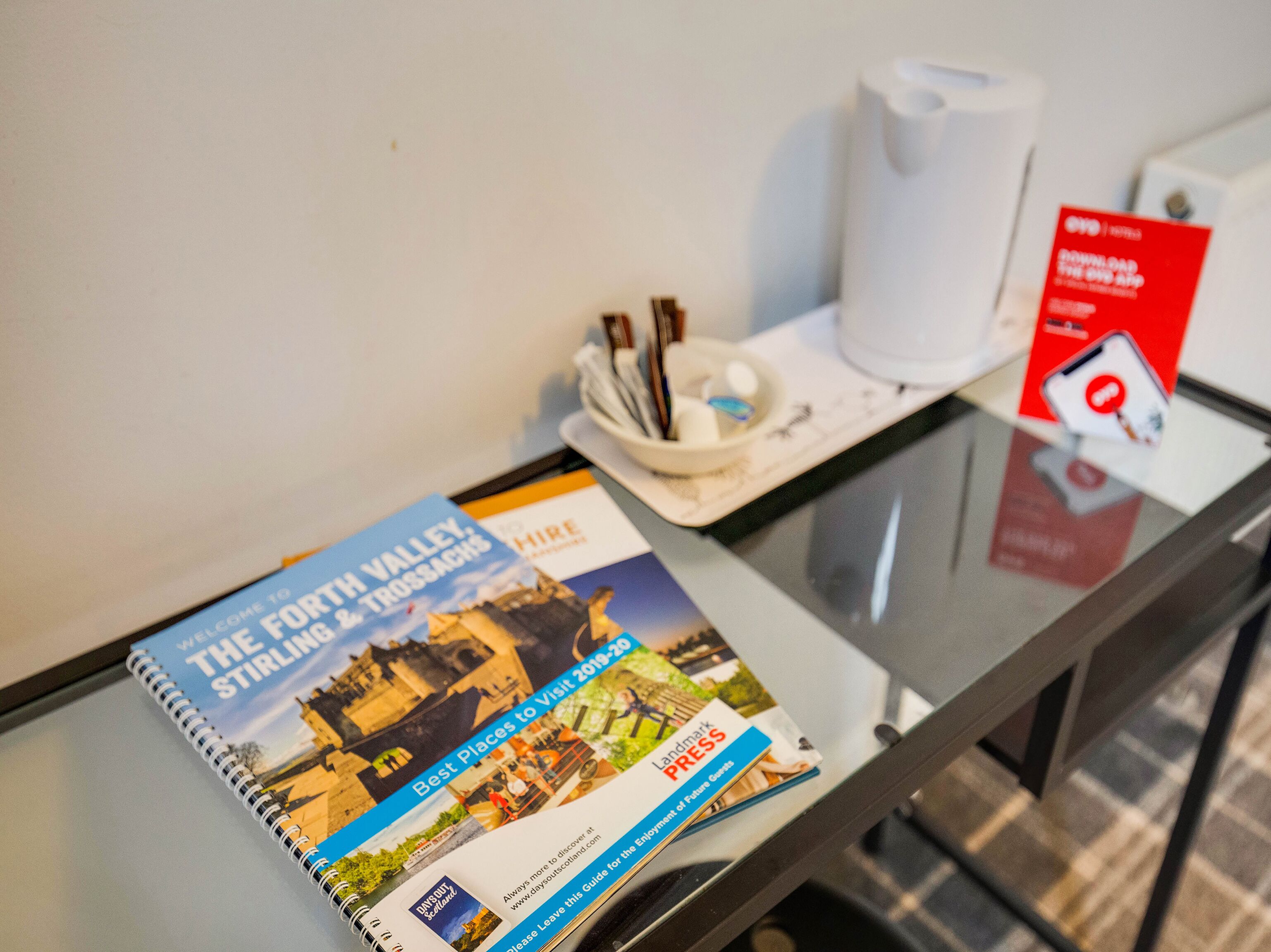 A brochure titled "The Stirling & Trossachs" on a glass table.