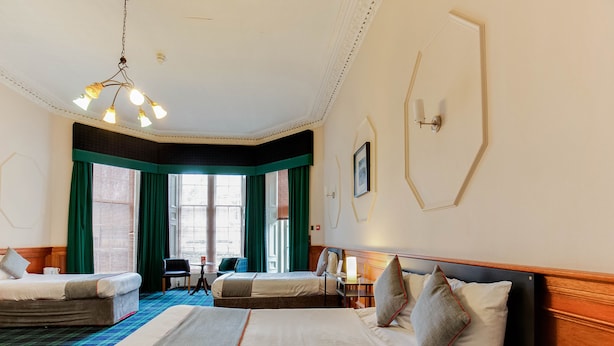 A hotel room with a large bed, two smaller beds, a desk, and a chair. - Lost Guest House Stirling (Stirling)