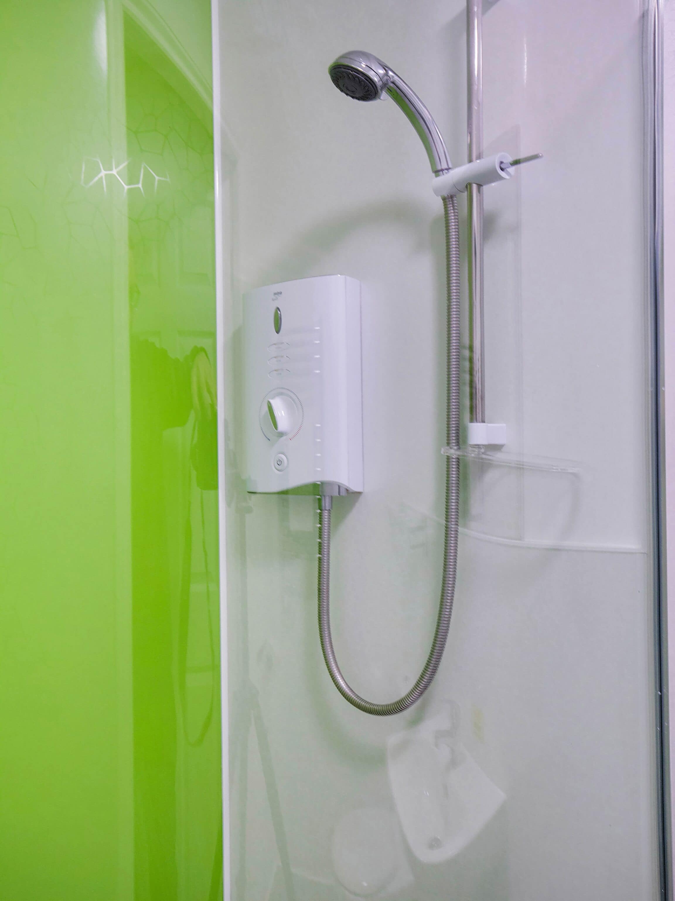 A shower with a handheld showerhead and a wall-mounted control panel.