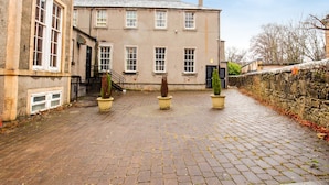 A historic building with a paved courtyard, stone wall, and two potted plants. - Lost Guest House Stirling (Stirling)