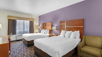 A hotel room with two beds, a desk, a chair, and a large window with curtains.