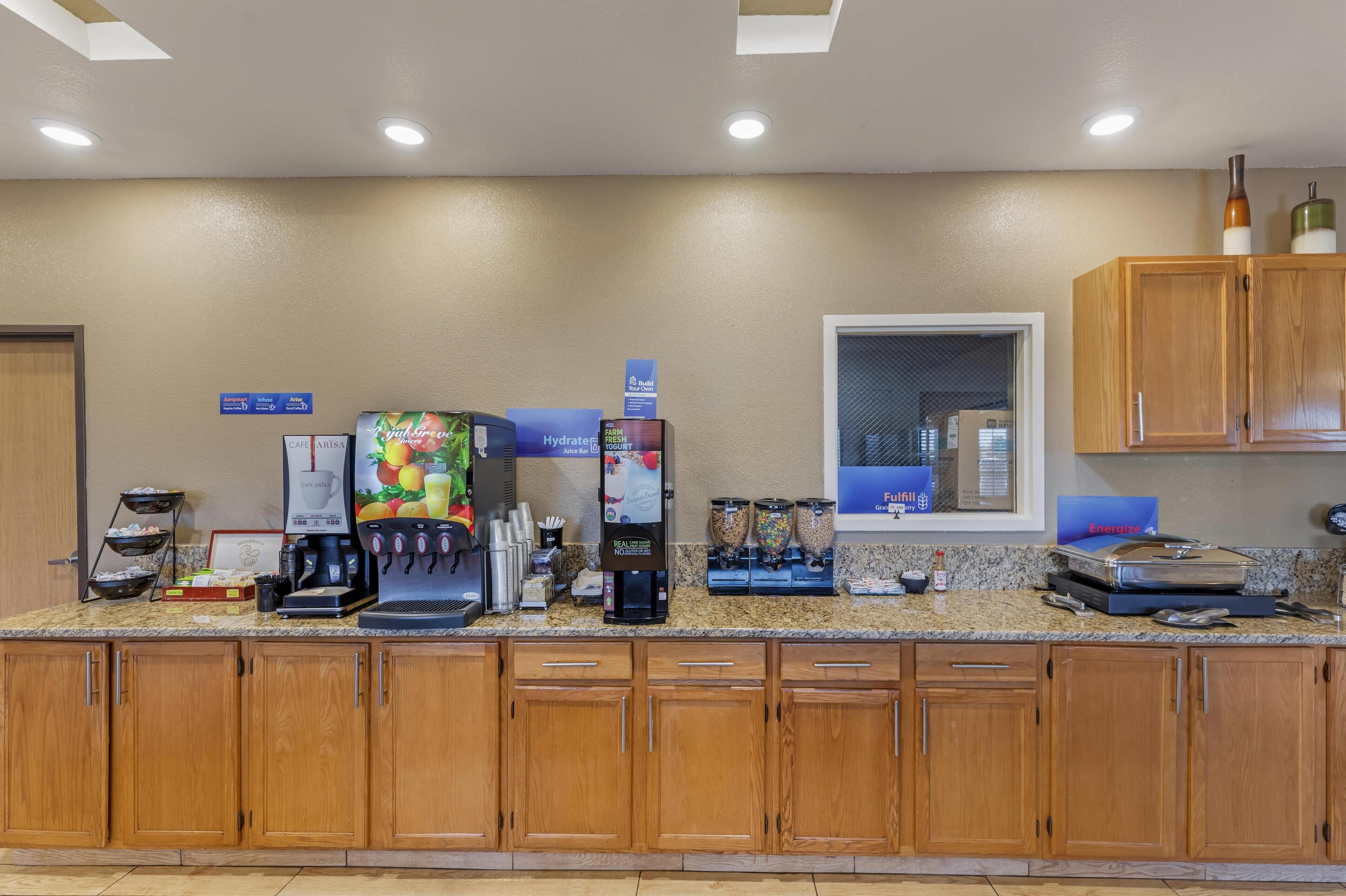 Zona de recepción de un hotel con máquina de café, dispensador de zumo y diversas comodidades.