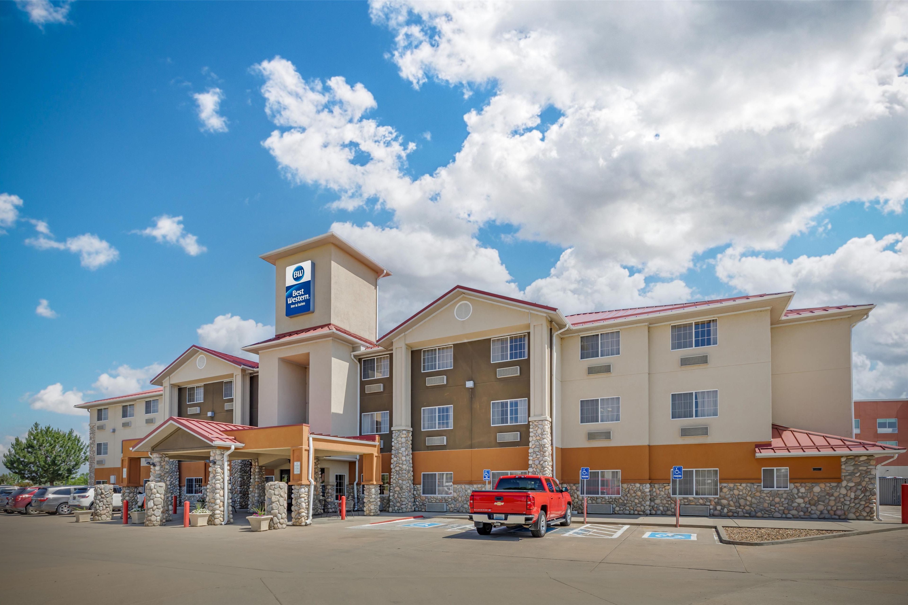 A hotel with a central tower, multiple floors, and a red truck parked in front.