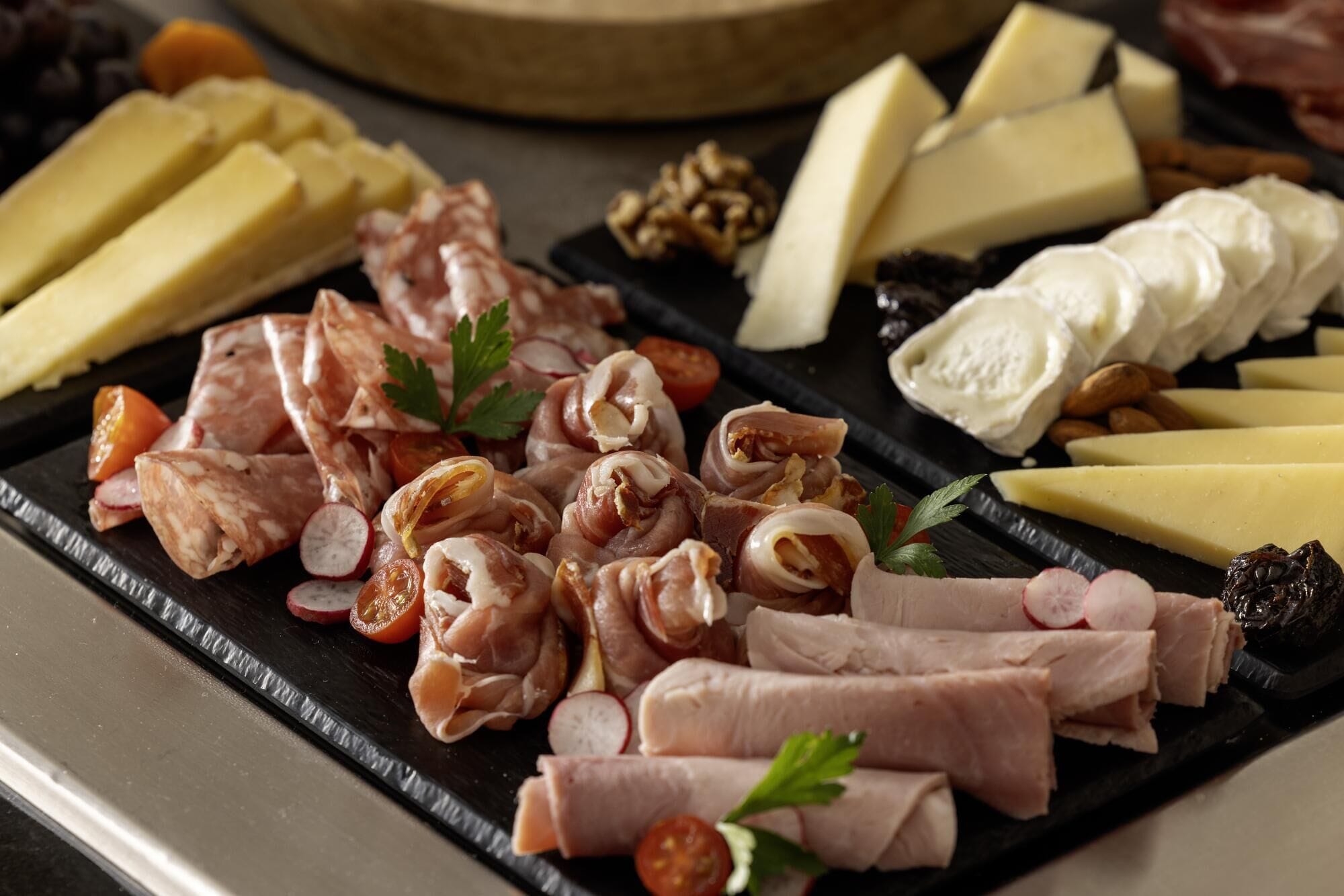 A charcuterie board with various meats, cheeses, and nuts.