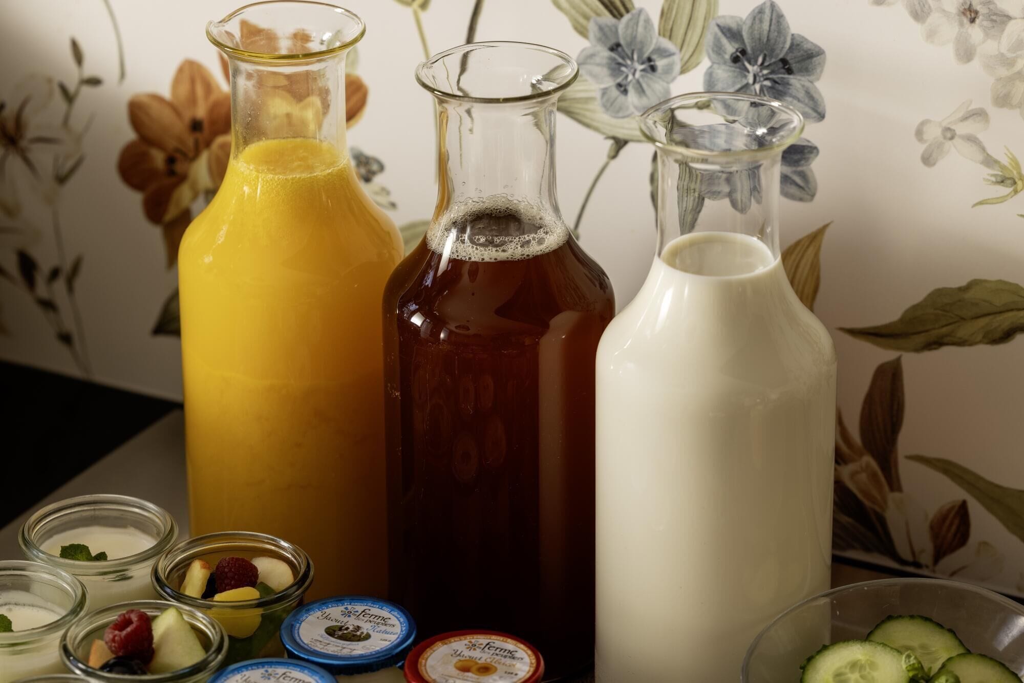 A variety of glass containers with different liquids, some with lids, and a white pitcher.