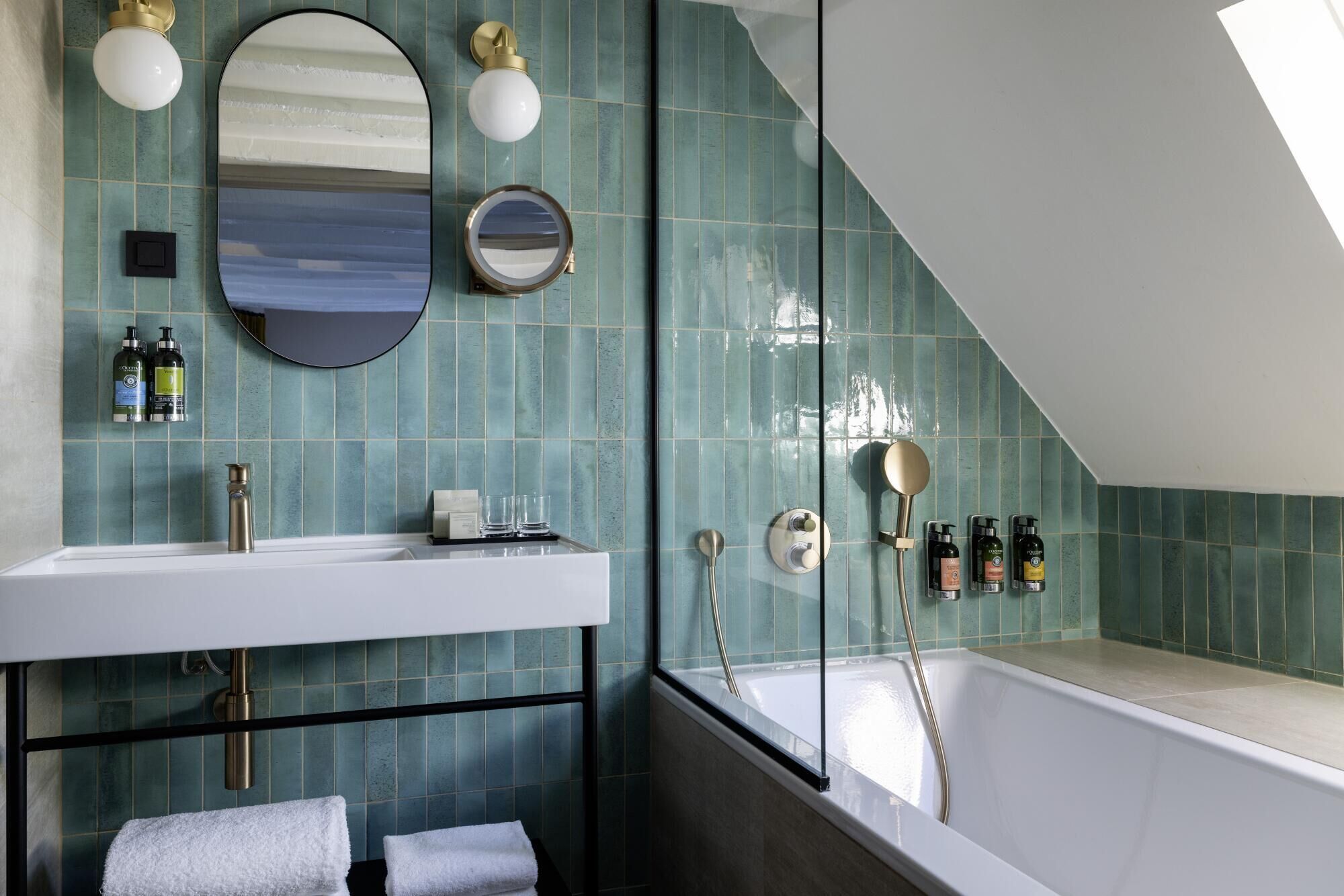 A modern bathroom with a freestanding bathtub, a large mirror, and a vanity with a sink and towel rack.