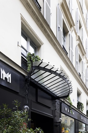 A building facade with a black awning, a sign reading "MAXIM OPERA", and a number "15" above the entrance. - Maxim Opéra (Paris)