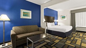 Hotellihuone, jossa on sininen tehosteseinä, sohva, sänky, pöytä ja lamppu.